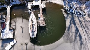 Water cleared of ice by deicer around sailboat Therapy and dock